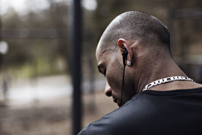 Rear view of male athlete wearing in-ear headphones in forest