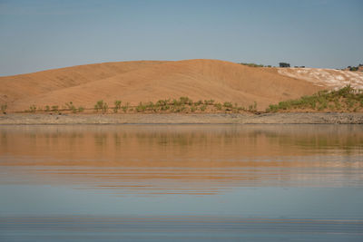 Desert like hill landscape with reflection on the water on a dam lake reservoir in terena, portugal