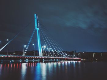 Illuminated bridge over river at night