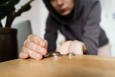 Midsection of woman holding coin on table