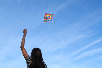 Low angle view of woman standing against blue sky