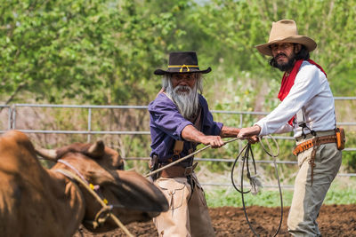 Farmers pulling bull on agricultural field