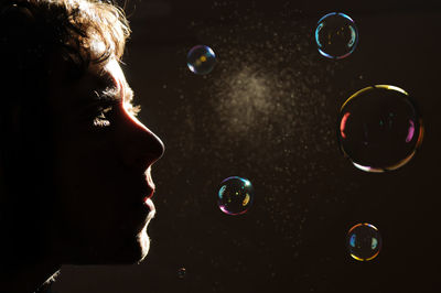 Close-up of man looking at bubbles flying in air