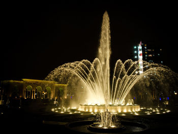 Illuminated fountain against sky at night