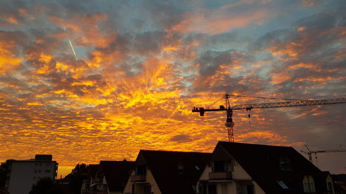 Low angle view of silhouette buildings against orange sky