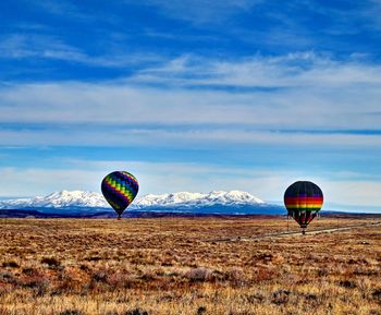 Hot air balloon flying over land against sky