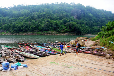 People by boats on river amidst trees