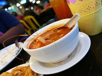 Midsection of man sitting by soup on restaurant table