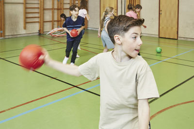 Boy throwing ball during pe class in school gym