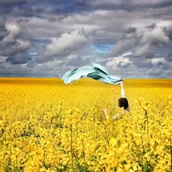 Scenic view of oilseed rape field against cloudy sky