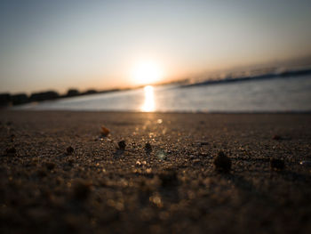 Surface level of beach against sky during sunset