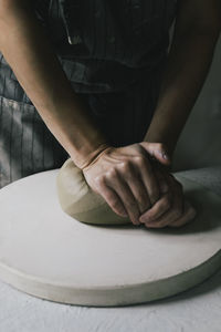 Midsection of craftswoman kneading clay in workshop