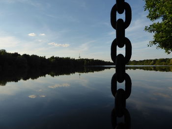 Silhouette of tree by lake against sky