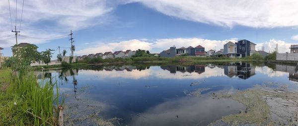 Scenic view of lake by buildings against sky