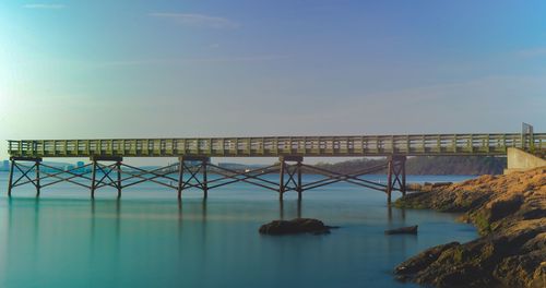 Bridge over river against sky in city