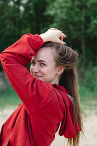 Candid portrait of a young caucasian woman in red clothes playing with her hair, posing