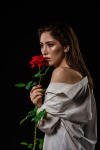 Woman holding red rose against black background