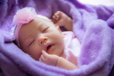 Close-up of newborn baby girl sleeping under blanket at home