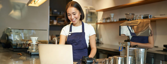 Portrait of young woman using mobile phone while standing at home