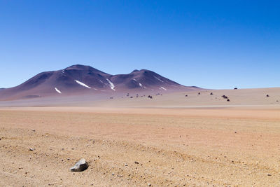 Scenic view of desert against clear blue sky