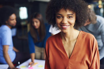 Portrait of smiling businesswoman while colleagues in background