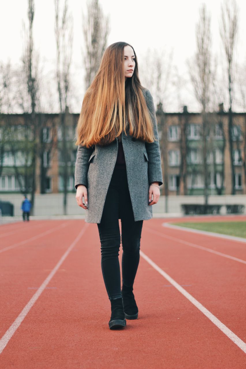 full length, real people, young adult, long hair, focus on foreground, standing, one person, women, hairstyle, clothing, day, lifestyles, young women, hair, front view, adult, beautiful woman, outdoors, warm clothing