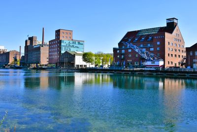 Buildings by river against sky