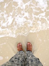 Low section of man standing on beach