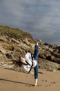 Woman doing taekwondo on the beach giving a kick to the air