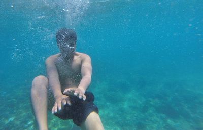 Shirtless man swimming underwater