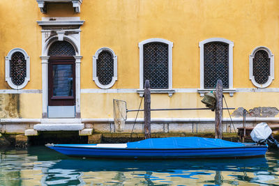 Boats moored on canal against building