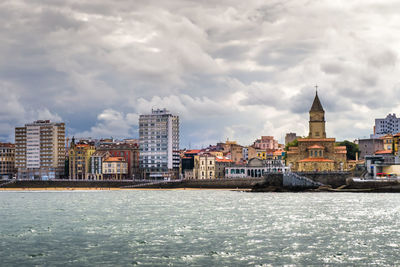 River by cityscape against sky