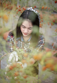 Young woman sitting by cherry plant