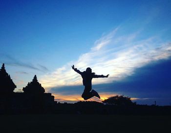 Silhouette of man with arms raised against sky