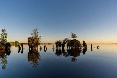 Scenic view of lake against clear sky at sunset