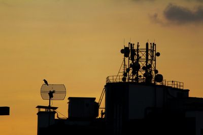 Low angle view of silhouette crane against sky during sunset