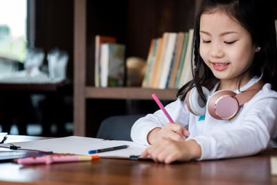 Close-up of girl writing on book at desk