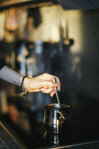 Cropped image of hand stirring spoon in container