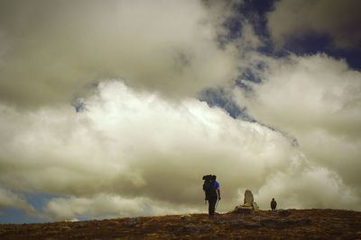 Woman standing on landscape against cloudy sky