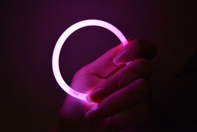 Close-up of hand holding camera against black background
