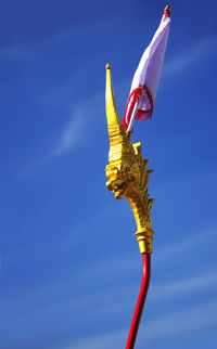 Low angle view of flag on dragon pole against clear blue sky