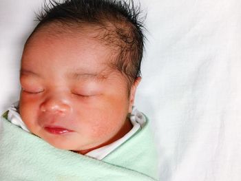 Close-up of baby sleeping on bed at home