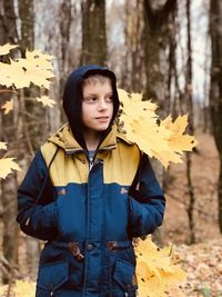 Boy looks fascinatingly standing on a background of autumn forest and yellow maple leaves