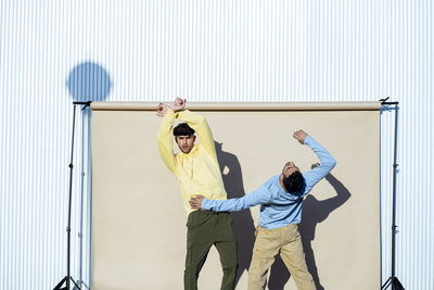 Male dancers performing together by backdrop