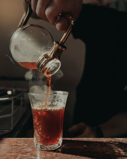 Midsection of person pouring drink in glass