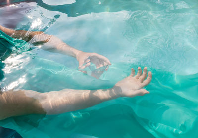 Cropped hand of person holding pyramid crystal in swimming pool