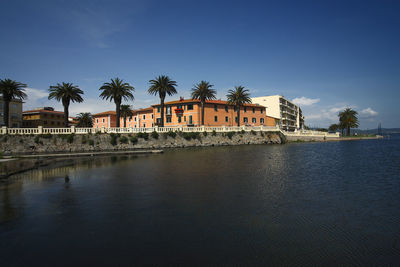 Building by lake against blue sky