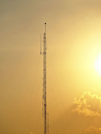 High antenna in screen of orange sky and sun scene