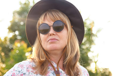 Outdoor portrait of a blonde middle-aged woman in hat and sunglasses. youth, wellness and lifestyle 