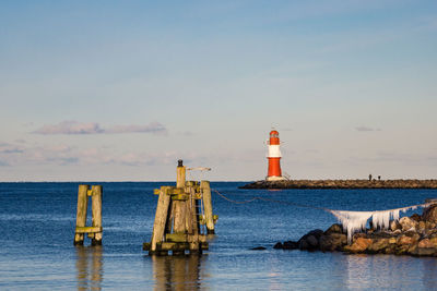 Lighthouse by sea against sky